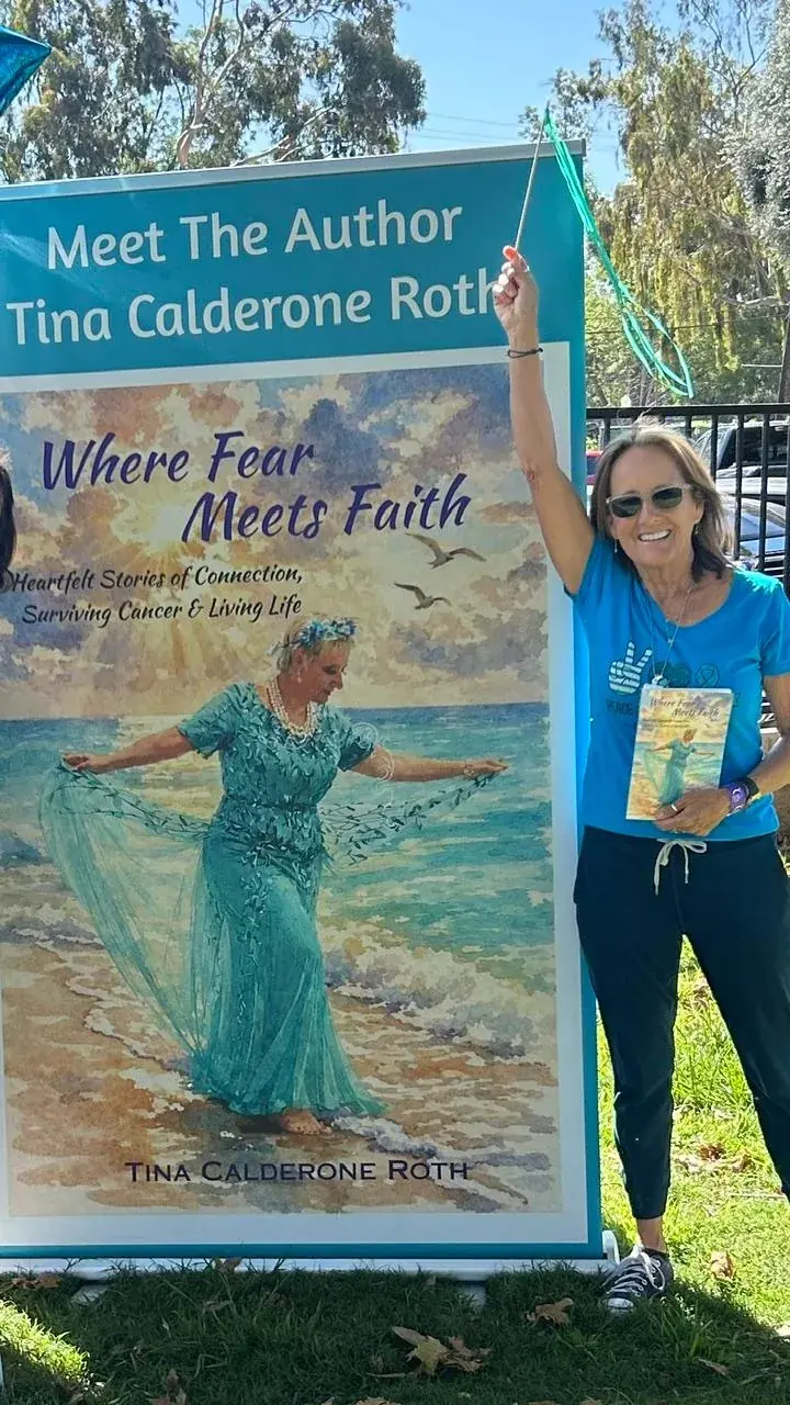 Tina at an outdoor Meet the Author event beside a large banner of her book cover.