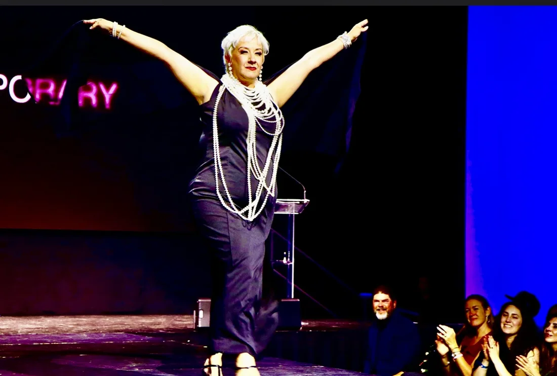 Tina walking the catwalk in a black gown at the Brave, Bold and Boundless survivor fashion show.